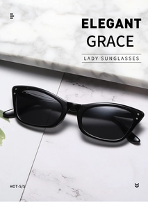 Close-up of retro black cat-eye sunglasses with silver rivet detail on white marble