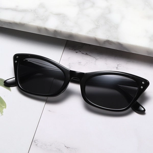 Retro black cat-eye sunglasses with silver metal rivets on a minimalist marble surface