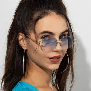 Detail of rimless octagonal sunglasses with gradient blue lenses and C-shaped metal hinge