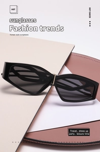 Detail of black irregular cat-eye sunglasses with gold metal accents and dark grey lenses