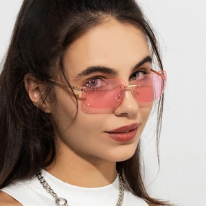 Dettaglio di occhiali da sole rettangolari rosa senza montatura con strass e aste dorate