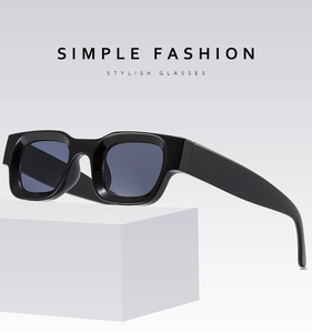 Detail of square black punk sunglasses with glossy thick frame on white block