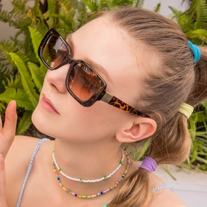 Classic rectangle tortoise shell sunglasses with golden hinges on a woman outdoors