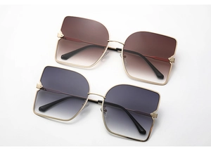 Détail de lunettes de soleil en métal avec verres dégradés marron et bleu et rivets d'or
