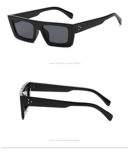 Détail de lunettes de soleil ovales noires avec rivets dorés sur les branches