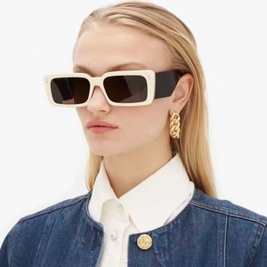 Fashionable rectangular cream white sunglasses with wide black temples worn by a model