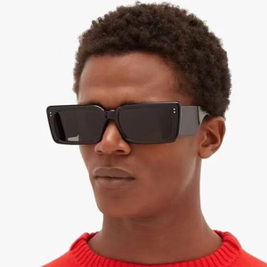 Fashionable black square sunglasses with silver accents worn by a model in red