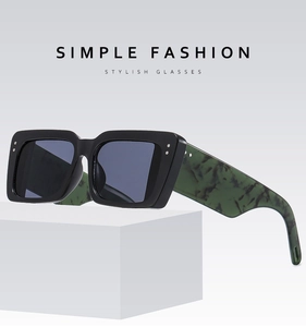 Detail of square sunglasses featuring green marble temples and decorative metal rivets