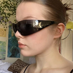 Detail view of the wide black frame with a golden star accent on these sunglasses
