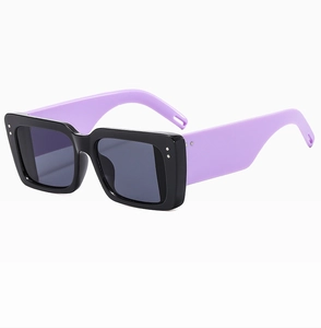 Detail of square sunglasses with black frames and lavender temples and silver rivets
