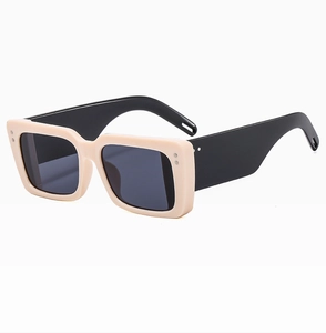 Detail of square sunglasses with cream frame, thick black temples and metal rivets
