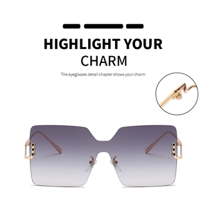 Detail of square oversized sunglasses showing golden metal hinges and gradient lenses