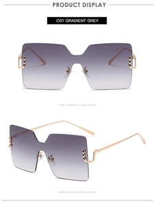 Detail view of large square gradient grey sunglasses with golden metal frame and accents