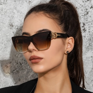 Detail of oversized gradient sunglasses featuring decorative golden double-ring hinges