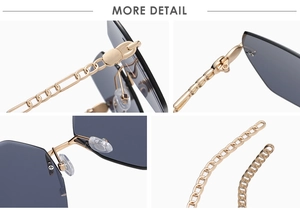 Detail of oversized rimless sunglasses with gold chain temples and grey lenses