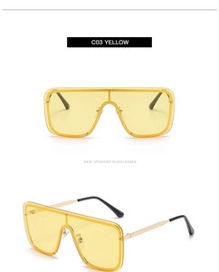 Detail view of oversized square shield sunglasses with yellow lenses and golden metal frame