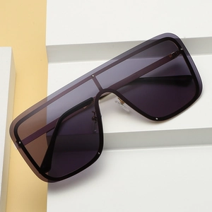 Oversized shield sunglasses with dark gradient lenses and black frames on a geometric stand
