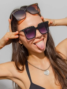 Detail of square sunglasses with gold studs and a silver bead necklace with a heart pendant