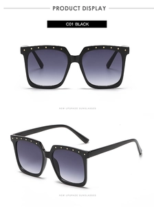 Macro view of square oversized sunglasses featuring golden rivet studs and gradient lenses