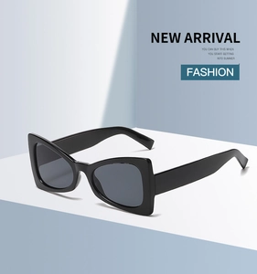 Detail of black geometric cat-eye sunglasses with wide temples on a minimalist background