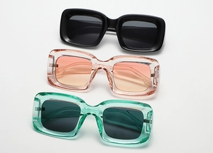 Detailed view of three square sunglasses in black, gradient peach, and neon green colors