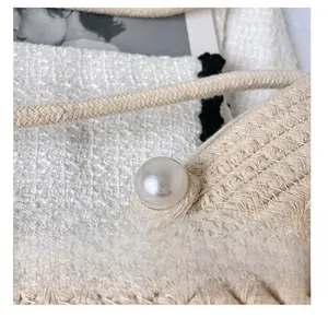 Detailed macro view of beige woven cotton bag featuring a large decorative pearl accent