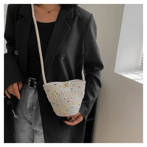 Detail of white crochet crossbody bag featuring colorful dots and a large pearl clasp