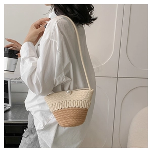 Detail of hand-woven straw crossbody bag with pearl clasp and bicolor cotton design