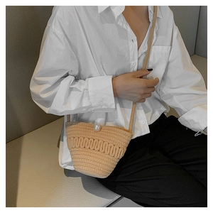 Close-up of woven bucket bag with wave texture and elegant white pearl fastener