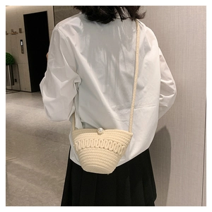 Detail of crossbody woven bag with elegant large pearl buckle on a beige cotton strap