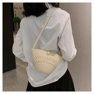 Detail of cream woven crossbody bag with wave texture and elegant pearl closure charm