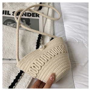Detail of off-white woven mini bucket bag featuring a large pearl clasp and rope strap