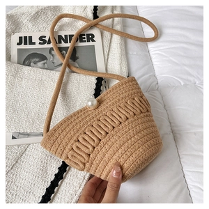 Close-up of khaki crochet crossbody bag with pearl button closure and woven texture