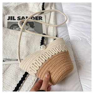 Detail of two-tone woven straw bucket bag with elegant pearl clasp and thin strap