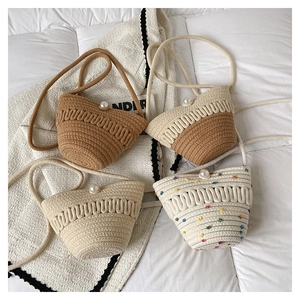 Detail of mini straw woven crossbody bags with large pearl closure in various earthy tones