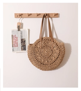 Détail du sac à bandoulière rond en paille avec texture ajourée et lanière marron