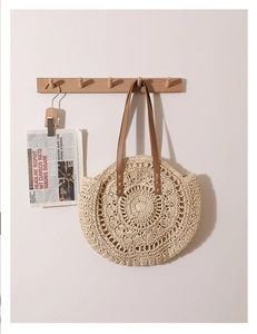 Détail du sac panier en paille tissé avec motifs circulaires et anses en cuir marron