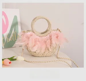 Détail du sac en paille avec plumes roses et poignée ronde pour les vacances à la plage