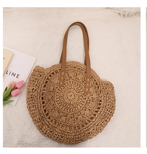 Détail du sac de plage rond en paille avec anses en cuir marron et texture tissée