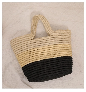 Detailed close-up of woven paper straw tote bag with contrast beige and black stripes