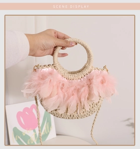 Détail du sac en paille avec garniture en plumes roses et poignée ronde en anneau