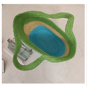 Top view of striped woven straw tote bag in green, beige and blue with textured weave