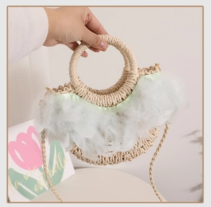 Détail du sac en paille demi-lune avec bordure en plumes blanches et poignée ronde