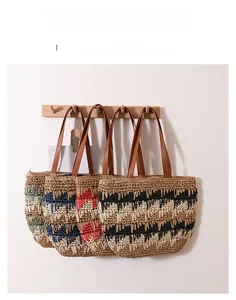 Hanging display of large woven straw tote bags with contrast wavy stripes and leather straps