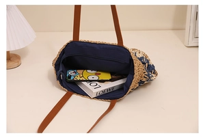 Detail view of the interior blue fabric lining and zipper pocket of the woven straw bag