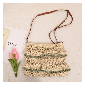 Détail du sac bandoulière en paille à volants avec couture verte et lanière marron