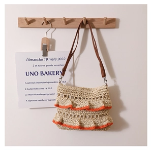 Détail du sac en paille tissé avec des volants orange et une fine bandoulière marron
