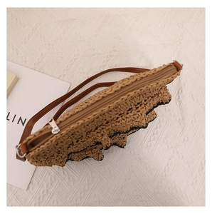 Détail d'un sac en paille avec fermeture éclair, bandoulière en cuir et bords à volants
