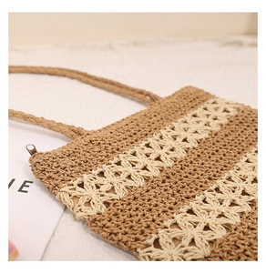Detail of hollow floral knit pattern and zipper closure on a straw tote bag