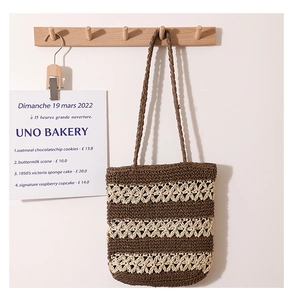 Close-up of handmade woven straw tote bag with intricate hollow patterns and brown stripes